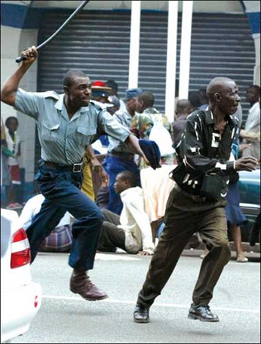 A Zimbabwean police officer attacks a fleeing pro-democracy demonstrator