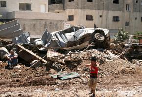 A young Palestinian boy runs from the scene of destruction after an Israeli assault on a Gaza refugee camp